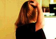 a woman in a black shirt is scratching her head with her hand