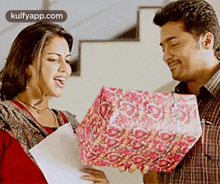 a man is giving a gift to a woman who is holding a notebook .