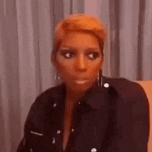a woman in a black jacket is sitting on a couch making a funny face .