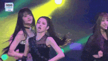 a group of girls are dancing on a stage in front of a yellow light .