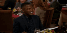 a man in a suit is sitting at a table in a restaurant looking at a menu