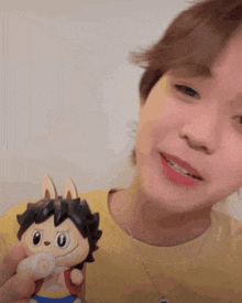 a person in a yellow shirt is holding a small toy