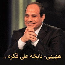 a man in a suit and tie is smiling with a foreign language behind him