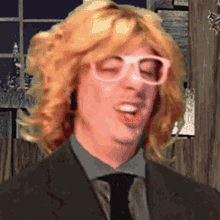 a man with blonde hair wearing glasses and a suit and tie