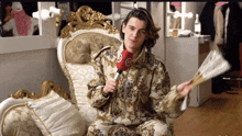 a man sitting in a chair holding a fan and a microphone with the letter g on it