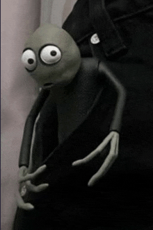 a cartoon character with big eyes is sitting on a person 's leg .