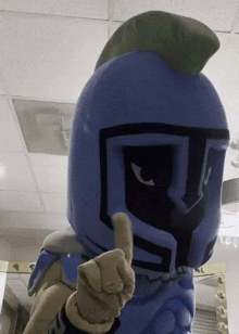 a mascot wearing a blue helmet giving a thumbs up sign