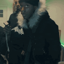 a man wearing a black jacket with a fur hood sticks out his tongue