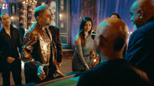 a group of people standing around a table with a woman in a blue dress