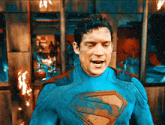a man in a blue superman costume stands in front of a wall