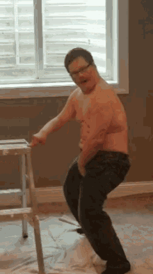 a shirtless man is standing on a ladder in a room