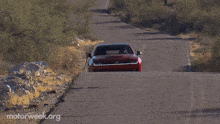 a red car is driving down a dirt road with motorweek.org written on the bottom