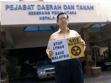 a man holds up a sign that says save malaysia
