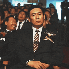 a man in a suit is sitting in front of a crowd