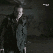 a man in a black jacket is standing in a dark room in a blurry photo .