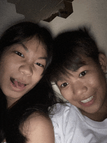 a boy and a girl are posing for a picture and the girl is sticking her tongue out
