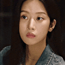 a close up of a woman wearing a denim jacket looking at the camera .