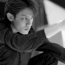 a black and white photo of a young man sitting down
