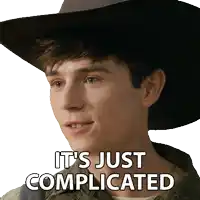 a young man wearing a cowboy hat has the words it 's just complicated written on his face