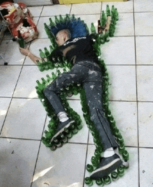 a man with a blue mohawk is laying on the floor surrounded by bottles