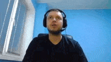 a man wearing headphones is sitting in front of a blue wall .