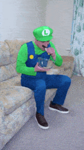 a man dressed as luigi is sitting on a couch