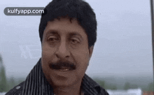 a man with a mustache is making a funny face while looking at the camera .