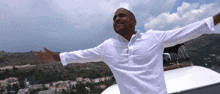 a man in a white shirt with his arms outstretched in front of a city