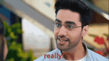 a man with glasses and a beard is smiling and says really