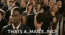 a man in a suit and tie is sitting in a crowd of people .