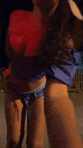 a woman in a crop top and shorts is dancing in front of a wooden fence