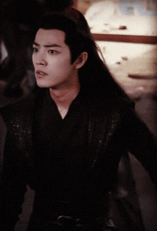 a man with long hair is wearing a black top