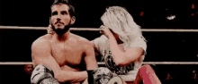 a woman is sitting on a man 's lap in a boxing ring .