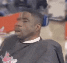a man is sitting in a barber chair with his eyes closed and his mouth open .