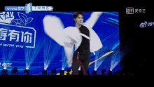 a man in a white jacket is dancing on a stage in front of a sign that says vivo s7