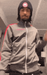 a man wearing a beanie and a grey jacket is dancing