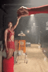 a woman in a red dress is standing in a room holding a large hand .