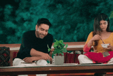 a man and woman are sitting at a table eating