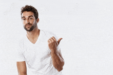 a man in a white t-shirt is pointing to the side