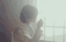a woman is sitting in front of a window drinking a cup of coffee .