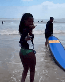 a woman standing on a beach holding a surfboard that says mcda