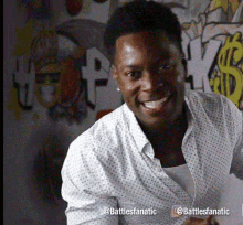 a man in a white shirt is smiling in front of a wall with graffiti that says hey