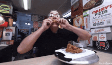 a man is eating fried chicken in a restaurant with massey 's pizza boxes on the wall