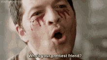 a man with blood on his face is making a funny face and asking who is your prettiest friend .