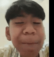 a young boy with his eyes closed is making a funny face .