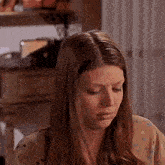 a woman with long brown hair is sitting in front of a table with her eyes closed .