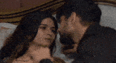 a man kisses a woman on the forehead while laying in bed