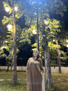 a woman wearing a dress that says abercrombie is standing in a park at night