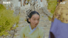 a woman in a yellow kimono is making a funny face while standing on a set of stairs .