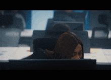a woman sitting in front of a computer with her head resting on her desk